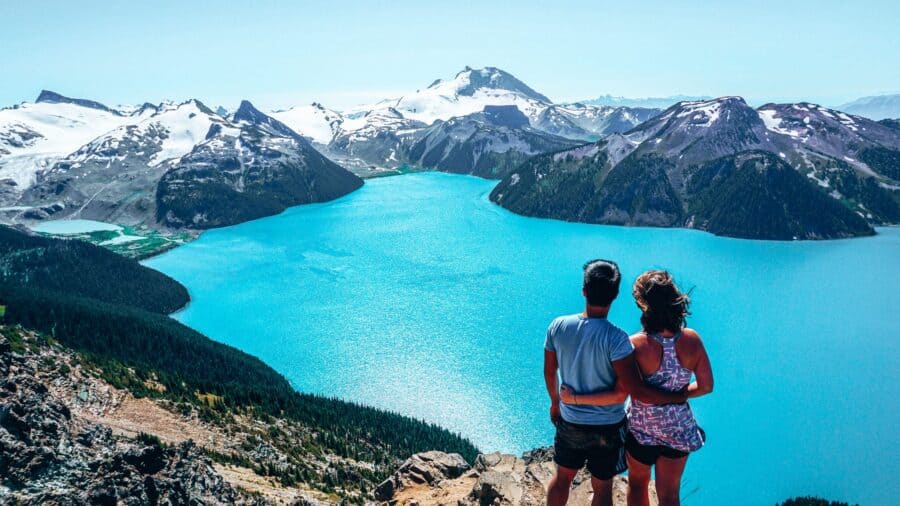 Hikers on a trail above a turquoise alpine lake